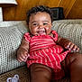 Zalayna is registered to the contest to win money with this photo: baby, child, closeup, couch, curly_hair, cute, drool, furniture, happy, indoor, infant, pacifier, person, plush, portrait, red_dress, sitting, skin, smiling, wood_paneling