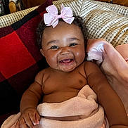 Zalayna is registered to the contest to win money with this photo: baby, blanket, cheeks, child, couch, cozy, curly_hair, cute, drool, happy, indoors, infant, pillow, pink_bow, portrait, red_and_black, relaxing, skin, smiling, toddler