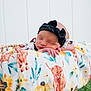 baby, newborn, sleeping, headband, black_bow, blanket, floral_pattern, animal_pattern, basket, woven, outdoor, grass, white_fence, peaceful, resting, infant, cute, soft, portrait, child