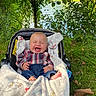 baby, infant, child, laughing, smiling, stroller, blanket, outdoor, nature, greenery, water, lake, forest, grass, plaid_shirt, jeans, portrait, seated, sunlight, happy
