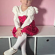 Aurora-belle is registered to the contest to win money with this photo: child, girl, pigtails, bows, white_top, red_skirt, white_socks, white_shoes, storage_unit, pink_wall, indoor, portrait, sitting, calm_expression, shadow, carpet, earrings, home, furniture, cute