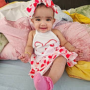 Ayra is registered to the contest to win money with this photo: baby, child, smiling, dress, headband, bow, heart_pattern, pink_socks, bracelet, bed, pillow, colorful, happy, cute, indoor, infant, person, portrait, sitting, clothing