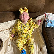 Gracelynn joined the competition — help win amazing prizes! baby, baby_wipes, bear_pattern, blanket, blue_socks, bow, child, couch, cozy, cute, happy, indoors, infant, living_room, person, playful, seated, smiling, soft_fabric, yellow_clothing