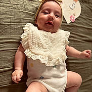 Marley-Rei joined the competition — help win amazing prizes! baby, infant, headband, bow, bib, lying_down, bedspread, soft_texture, cute, chubby_cheeks, smiling, clothing, skin, hand, foot, decor, flower, portrait, child, indoors