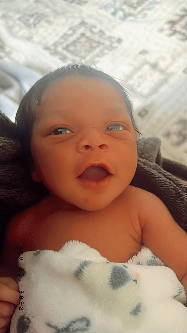 Köa is registered to the contest to win money with this photo: baby, baby_toddler_clothing, cheek, child, chin, comfort, eye, eyebrow, eyelash, finger, flash_photography, happy, head, iris, lip, mouth, nose, person, skin, smile