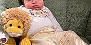 Jason is registered to the contest to win money with this photo: baby, child, stuffed_animal, lion, plush_toy, pajamas, paw_prints, armchair, green, cozy, cute, indoor, childhood, infant, soft_toys, relaxing, furniture, person, portrait, comfort