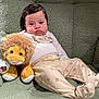 baby, child, stuffed_animal, lion, plush_toy, pajamas, paw_prints, armchair, green, cozy, cute, indoor, childhood, infant, soft_toys, relaxing, furniture, person, portrait, comfort