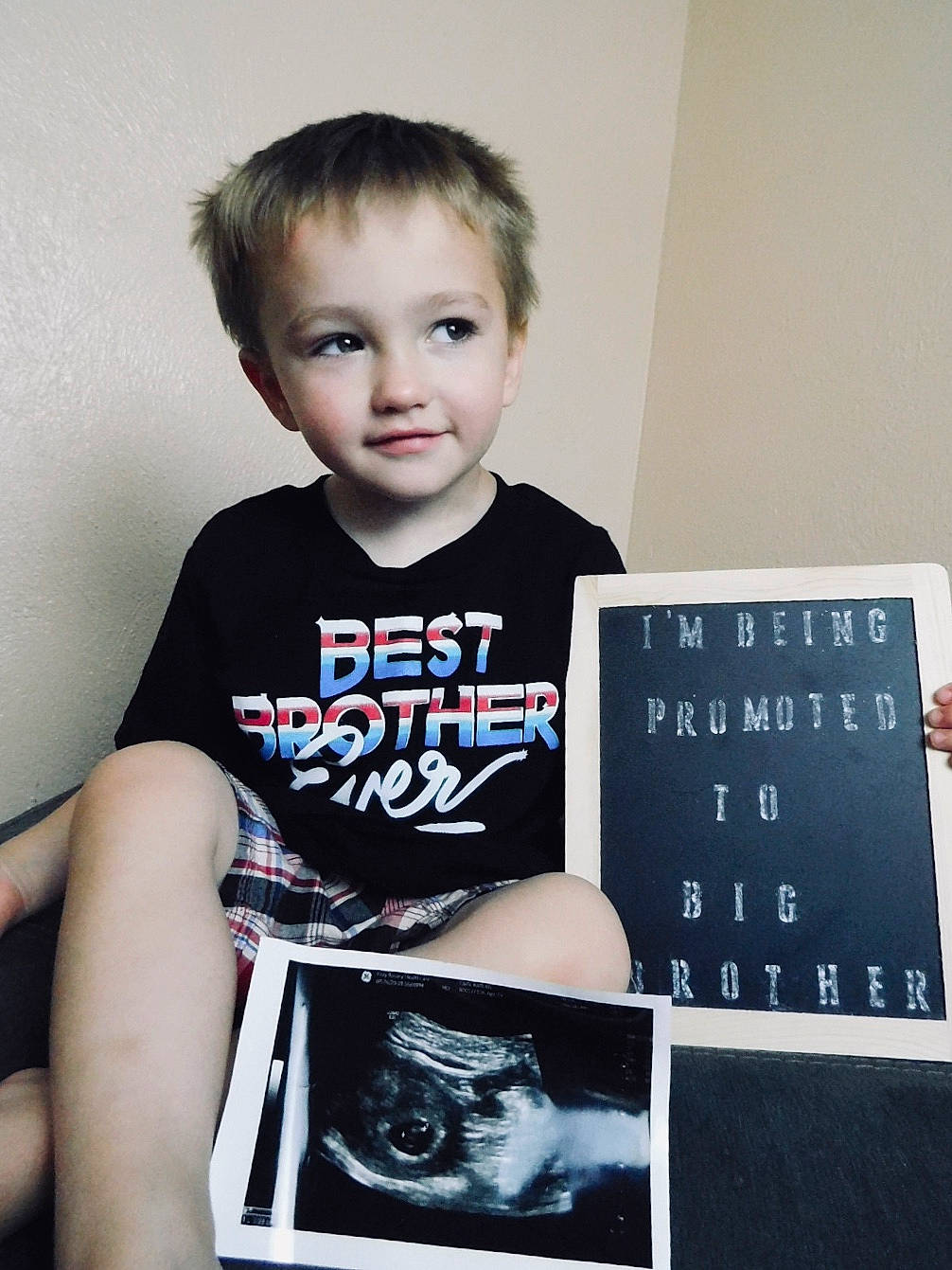 Dayton is registered to the contest to win money with this photo: active_shirt, baby_toddler_clothing, calendar, child, chin, cool, elbow, flash_photography, font, gadget, office_equipment, pattern, person, portrait_photography, room, sitting, sleeve, smile, t_shirt, toddler