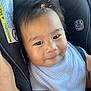 baby, child, car_seat, bib, smile, face, infant, clothing, seatbelt, safety, cute, skin, hair, indoor, warning_label, human, young_child, portrait, seat, comfort