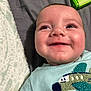 baby, child, smiling, face, blue_eyes, shirt, embroidery, airplane, blanket, bed, fabric, closeup, infant, happy, cute, person, portrait, lying_down, indoors, soft_texture