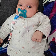 Mélinda a rejoint le concours — aidez-le/la à gagner de superbes lots ! baby, beads, blanket, blue, clip, cozy, eyes, face, hand, indoor, infant, lying_down, onesie, pacifier, pacifier_chain, patterned_clothing, pillow, pink, soft_fabric, white