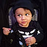 child, toddler, baby, face, black_clothing, hat, skeleton_outfit, stroller, safety_harness, pointing, curious, indoor, portrait, young_child, cute, expression, seat, black_background, person, closeup