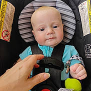 Ace is registered to the contest to win money with this photo: baby, car_seat, child, drool, hand, harness, infant, person, safety, seat_belt, toy, warning_label, blue_clothing, clip, face, head, straps, cute, indoor, closeup