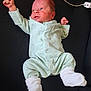baby, black_background, cable, clothing, cute, expressive, face, human, indoors, infant, lying_down, newborn, onesie, portrait, power_strip, raised_fist, resting, skin, small_hands, white_socks