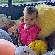 Eleanor joined the competition — help win amazing prizes! toddler, child, plush_toys, pink_clothing, cushions, indoor, window, soft_light, yellow_pillow, stuffed_animal, cute, portrait, cozy, seated, curious, baby, play_area, colorful, soft_texture, young_child