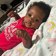 Niyari joined the competition — help win amazing prizes! baby, infant, blanket, red_clothing, rainbow_pattern, face, hand, lying_down, curious, indoors, soft_texture, cute, child, newborn, portrait, sleepwear, cozy, skin, head, young