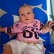 Juliette participe au concours pour gagner de l'argent avec cette photo : baby, child, infant, shirt, shorts, clothing, blue_chair, pattern, drool, face, eyes, arm, hand, sitting, indoor, cute, small_person, relaxing, looking_up, casual