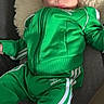 adidas, apparel, baby, bright, casual, child, clothing, comfortable, cute, face, foot, fuzzy_blanket, green_tracksuit, indoor, infant, person, portrait, relaxed, sitting, young