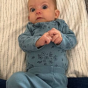 Novalea is registered to the contest to win money with this photo: baby, infant, blue_clothing, floral_pattern, blanket, lying_down, hands, face, eyes, curious, cute, indoor, soft_lighting, child, portrait, expression, cozy, person, newborn, young_child