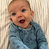 baby, infant, smile, blue_clothing, onesie, face, eyes, happy, joy, lying_down, blanket, pattern, cute, expression, child, young, skin, head, mouth, person