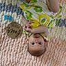 baby, infant, toy, pacifier, blanket, patterned_clothing, yellow, blue, wooden_plaque, floor, cute, child, lying_down, portrait, indoors, face, hand, foot, young_child, milestone
