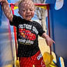 child, toddler, smiling, playground, slide, outdoor, daylight, clothing, shorts, tshirt, red, black, yellow, blue, sunlight, shadow, person, happy, cute, summer