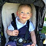 George is registered to the contest to win money with this photo: baby, baby_clothing, blue_eyes, child, comfort, cute, happy, infant, navy_outfit, outdoor, person, portrait, seat, seatbelt, smile, stroller, sunlight, suspenders, toddler, white_shirt