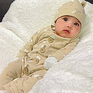 Sabreen joined the competition — help win amazing prizes! baby, infant, pajamas, hat, blanket, white_blanket, cozy, cute, indoors, portrait, child, soft_texture, sleepwear, seated, looking_up, warm_clothing, comfort, face, expression, small