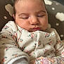 baby, child, closeup, cozy, cushion, fabric, face, floral_clothing, head, indoors, infant, newborn, onesie, pattern, peaceful, portrait, resting, skin, sleeping, soft