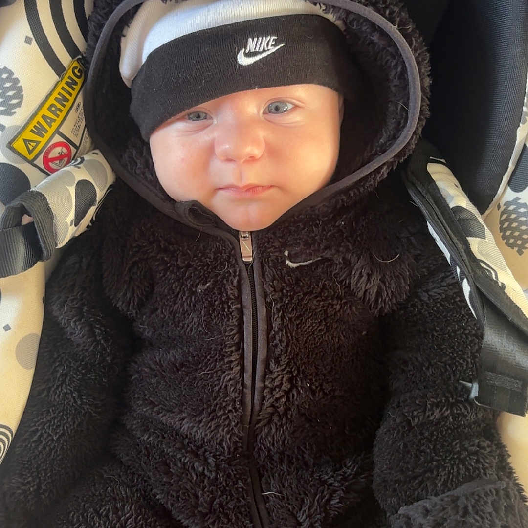 Maëlyo participe au concours pour gagner de l'argent avec cette photo : baby, black_onesie, blue_eyes, car_seat, child, cute, face, hooded_jacket, indoors, infant, nike_headband, patterned_fabric, portrait, seatbelt, sitting, small_person, soft_texture, warm_clothing, winter_clothing, zipper