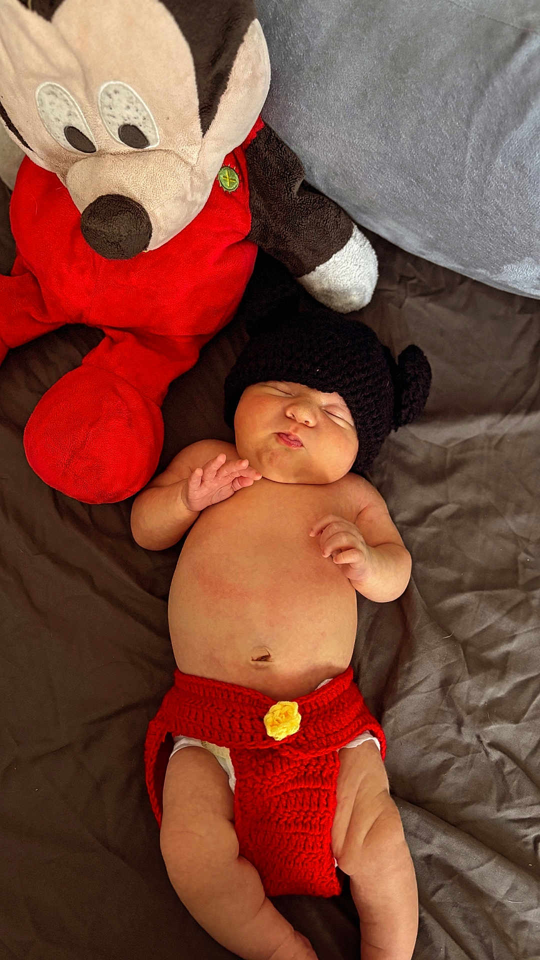 Maëlyo a rejoint le concours — aidez-le/la à gagner de superbes lots ! baby, infant, plush_toy, mickey_mouse, knit_hat, crochet_clothing, red_clothing, diaper_cover, sleeping, peaceful, bedspread, soft_toy, cute, chubby, indoor, child, person, resting, cozy, toy