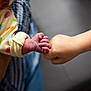 adult_hand, arm, baby, bond, child, closeup, clothing, connection, family, fingers, fist_bump, hand, heart, interaction, love, pattern, polka_dot, skin, sleeve, tenderness