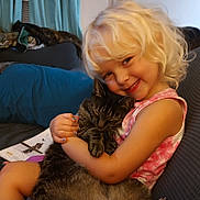 Allison joined the competition — help win amazing prizes! child, blonde_hair, smile, cat, tabby_cat, hugging, couch, indoor, cozy, happy, pet, person, sitting, book, curtain, furniture, home, nail_polish, tank_top, portrait