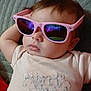 baby, child, sunglasses, pink, reflection, face, feet, clothing, lying_down, relaxed, indoor, cute, fashion, person, infant, portrait, soft_texture, blanket, casual, resting