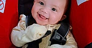 Memory is registered to the contest to win money with this photo: baby, child, infant, smiling, happy, car_seat, safety_harness, portrait, indoor, close_up, face, eyes, mouth, mitten, onesie, red, black, heart_icon, seated, automobile