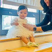 Hinaki joined the competition — help win amazing prizes! baby, child, woman, dress, window, indoor, bookshelf, wooden_furniture, socks, flower, glasses, smartwatch, smile, person, holding, curious, natural_light, casual, support, seated