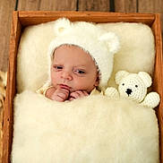 Léo participe au concours pour gagner de l'argent avec cette photo : baby, newborn, hat, bear_ears, wooden_box, blanket, crocheted_toy, teddy_bear, soft_texture, cozy, sleeping_baby, infant, cute, portrait, indoor, wood_floor, child, wrapped, hands, peaceful