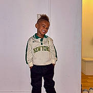 Kessim participe au concours pour gagner de l'argent avec cette photo : black_pants, casual_clothing, child, doorway, fashionable, full_body, hairstyle, hands_in_pockets, happy, indoor, minimalist, new_york, polo_shirt, portrait, smiling, sneakers, standing, white_wall, wood_floor, young_child