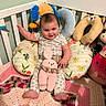 baby, crib, plush_toy, cushion, crocheted_bunny, blanket, child, smiling, indoor, person, cute, toy, colorful, soft, decor, happy, seated, head, foot, pajamas