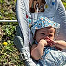 baby, child, infant, blue_dress, sun_hat, baby_chair, outdoor, sunlight, greenery, dandelion, cartoon, dog_cartoon, cute, summer_clothing, nature, portrait, face, hand, sitting, relaxing