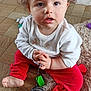 barefoot, child, closeup, curiosity, curly_hair, expression, floor, footwear, home, indoor, person, playful, red_pants, rug, shoe, shoelace, sitting, toddler, toy, white_sweater