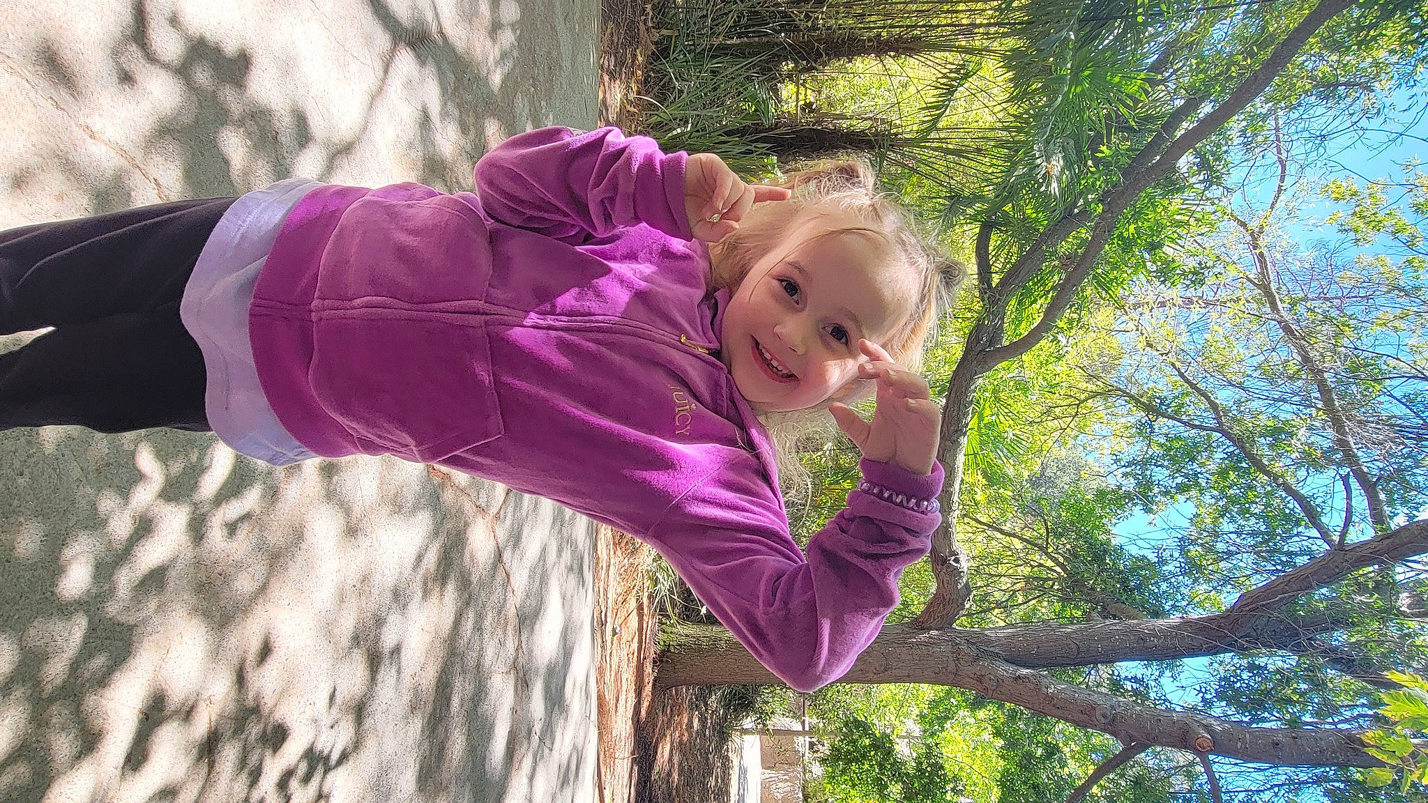 Chloe is registered to the contest to win money with this photo: baby_toddler_clothing, botany, child, face, fun, grass, happy, jacket, joy, leaf, leisure, magenta, people_in_nature, person, pink, plant, purple, smile, toddler, tree