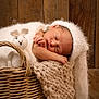 baby, newborn, sleeping, basket, knit_blanket, knit_hat, toy, bunny, wooden_background, cozy, cute, infant, soft_texture, peaceful, portrait, indoors, resting, child, wrapped, warm