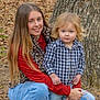 child, toddler, girl, outdoor, tree, autumn, leaves, nature, portrait, smile, casual_clothing, plaid_shirt, jeans, long_hair, blond_hair, blue_eyes, kneeling, sibling, family, young