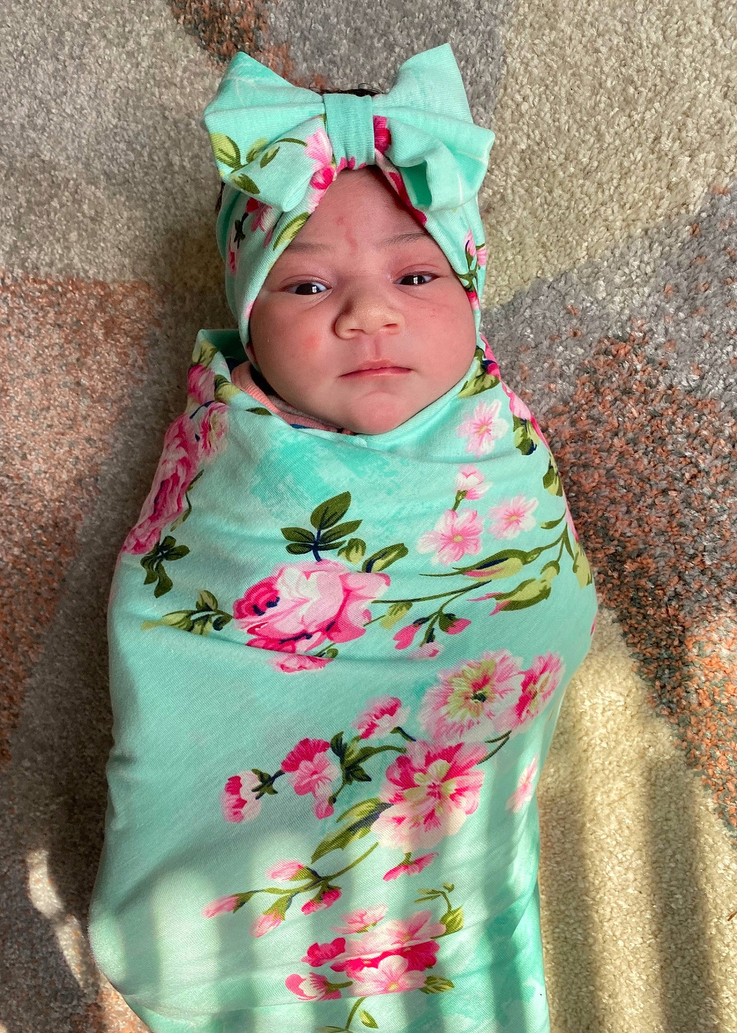 Raven is registered to the contest to win money with this photo: baby, child, clothing, design, dress, face, green, hair_accessory, head, headgear, headwear, outerwear, pattern, person, pink, plant, product, skin, smile, textile