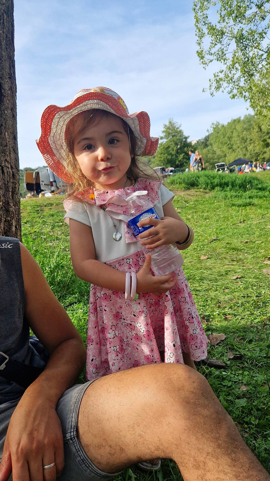 Louna participe au concours pour gagner de l'argent avec cette photo : dress, fun, grass, happy, hat, headwear, human_leg, lap, leisure, mammal, person, pink, plant, recreation, skin, sky, summer, sun_hat, thigh, toddler