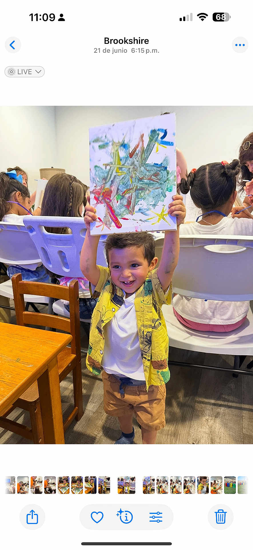 Enzo Toro is registered to the contest to win money with this photo: child, boy, painting, art_class, colorful, smiling, happy, indoor, wooden_table, chairs, people, kids, creative, drawing, playful, shirt, shorts, floor, hair, expression