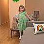 cat, child, couch, decor, furniture, girl, green_dress, happy, home, indoor, lamp, living_room, person, pet, pillow, rainbow, shamrock, smiling, table, wood_floor