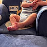 baby, child, blue_chair, hello_sign, indoor, furniture, person, infant, cute, home, seated, floor, wooden_cabinet, curious, hands, feet, portrait, casual_clothing, smiling, relaxed