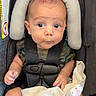 baby, infant, car_seat, child, blanket, face, head_support, clothing, camo_pattern, sitting, straps, safety_harness, cute, portrait, indoor, expression, person, young_child, soft_toy, comfort